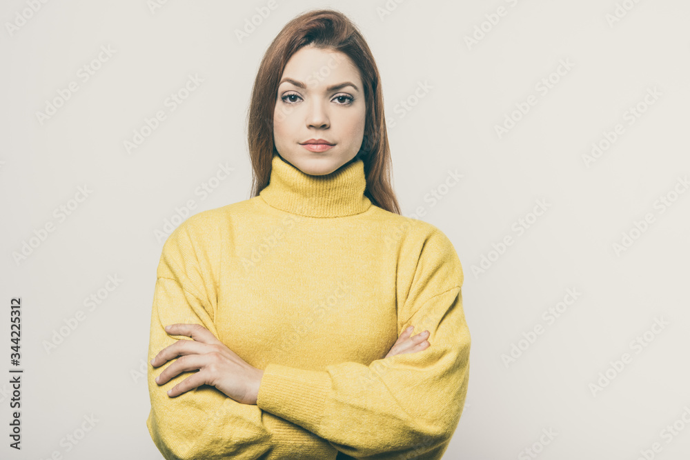 Obraz premium Confident young woman looking at camera. Portrait of beautiful serious young woman standing with crossed arms and looking at camera. Confidence concept