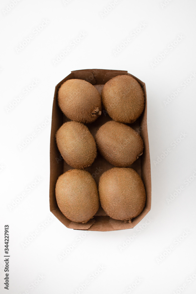 Whole brown kiwi fruits in carton box. Hairy fresh ripe kiwifruits. Closeup, top view. Fresh vegetables market concept Whole brown kiwi fruits in carton box. Hairy fresh ripe kiwifruits. Closeup, top view. Fresh vegetables market concept