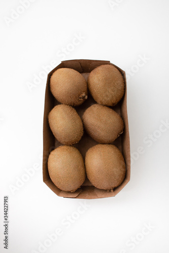 Whole brown kiwi fruits in carton box. Hairy fresh ripe kiwifruits. Closeup  top view. Fresh vegetables market concept