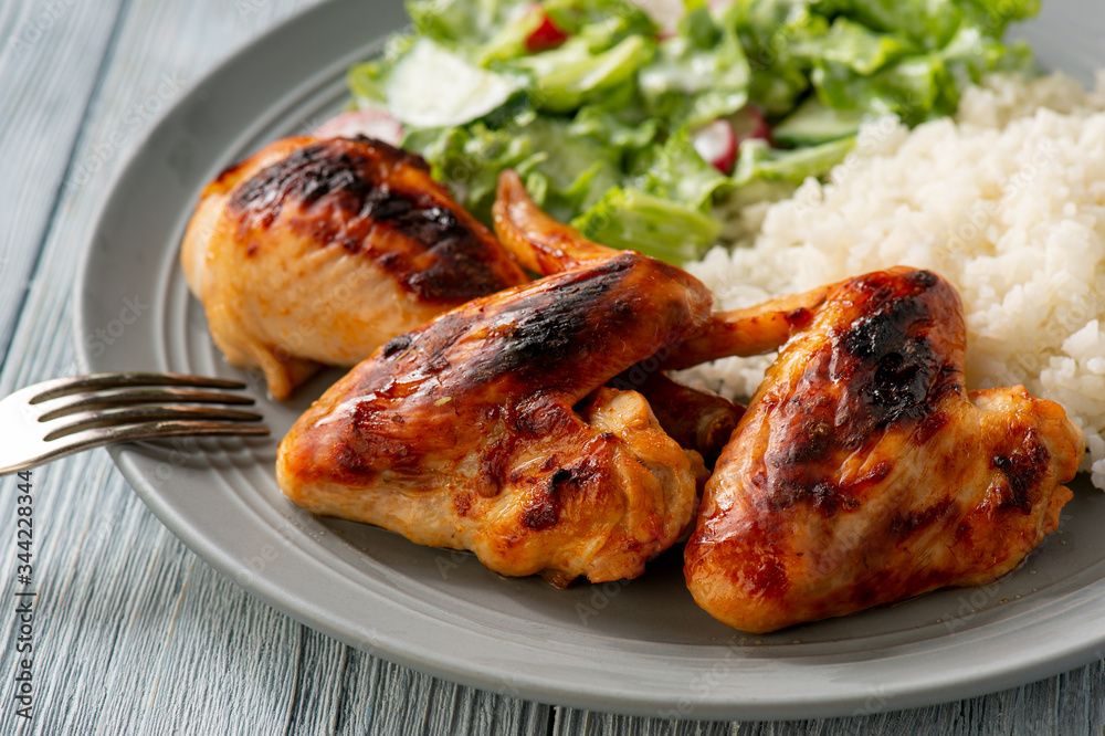 Grilled chicken wings and drumsticks, served with boiled rice and salad. Grilled chicken wings and drumsticks, served with boiled rice and salad.