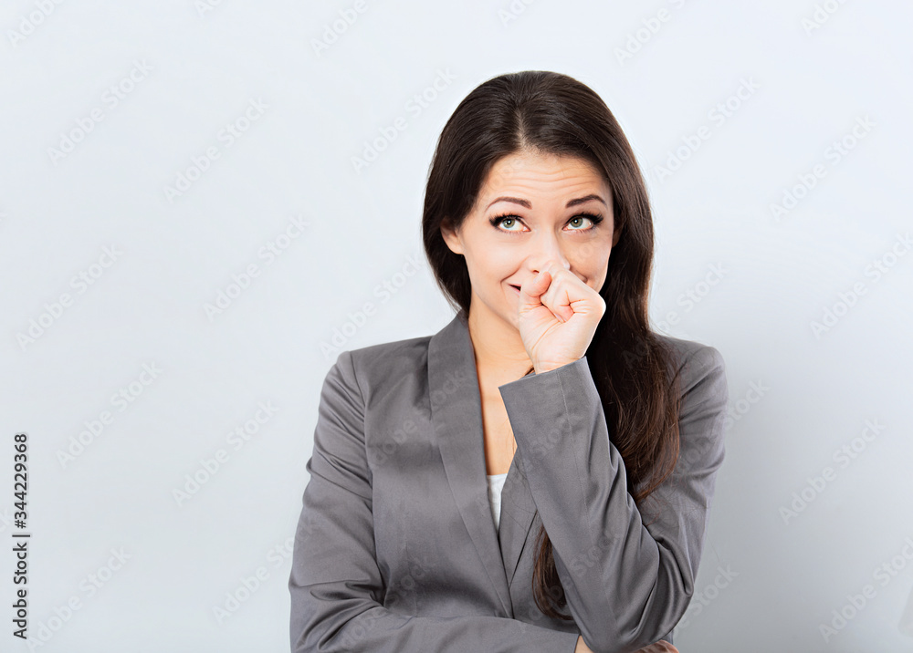 Beautiful smiling business woman in suit holding the hands the face and looking up on blue background portrait Beautiful smiling business woman in suit holding the hands the face and looking up on blue background portrait