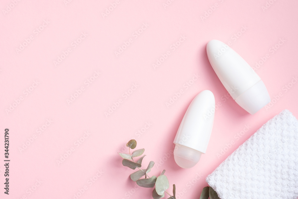 Blank roll-on deodorant bottles with eucalyptus and towel on pink background. Natural organic antiperspirant, female sweat protection product concept. Flat lay, top view Blank roll-on deodorant bottles with eucalyptus and towel on pink background. Natural organic antiperspirant, female sweat protection product concept. Flat lay, top view