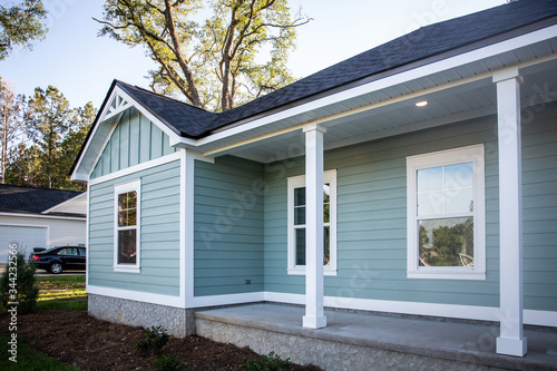 Front view of a brand new construction house with blue siding, a ranch style home with a yard