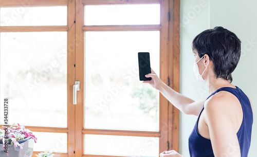 Woman using her mobile phone to make a video call inside her home during the Coronavirus quarantine