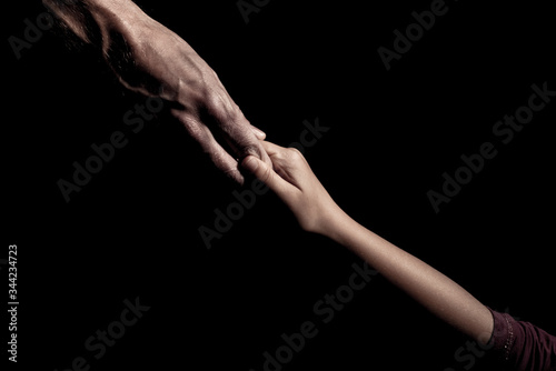 Old and young hands together on a black background holding hands