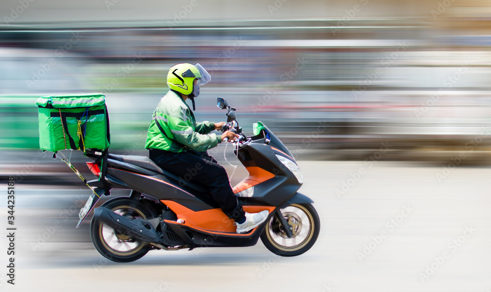 Food delivery staff drive motorbikes and rush to deliver food to customers who order food online. Due to the impact of the virus spread, most people live in Ban Nonthaburi, Thailand on 22/04/2020.