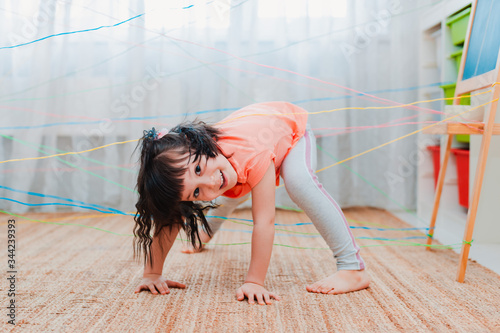 фотографія little girl child climbs through a rope web, a game obstacle quest indoors