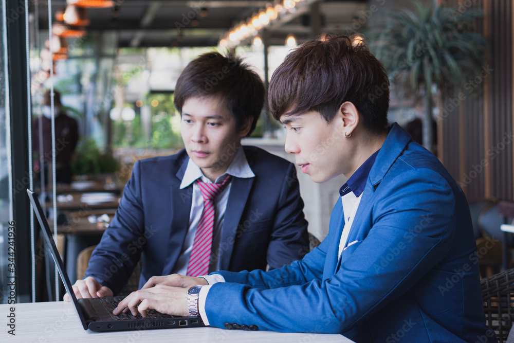 Business man explaining about project with caucasian colleague while typing keyboard with white screen laptop. Business man explaining about project with caucasian colleague while typing keyboard with white screen laptop.