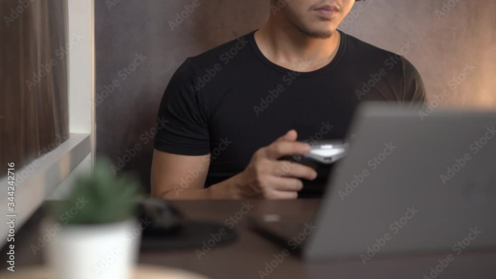 Asian man Gaming by using joy controller and laptop at home, hobby, technology and leisure time concept, Excited gamer holding joystick, home quarantine lifestyle during covid-19 pandemic, e-sports Asian man Gaming by using joy controller and laptop at home, hobby, technology and leisure time concept, Excited gamer holding joystick, home quarantine lifestyle during covid-19 pandemic, e-sports