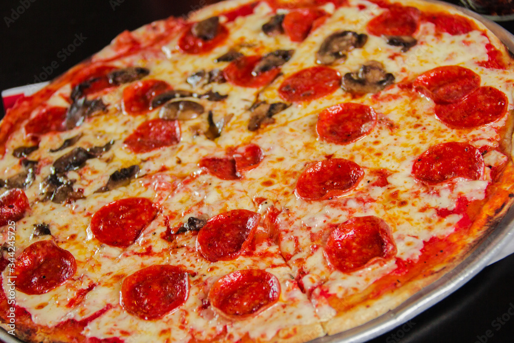 Pizza de pepperoni, mitad de champiñones, vista de cerca Pizza de pepperoni, mitad de champiñones, vista de cerca
