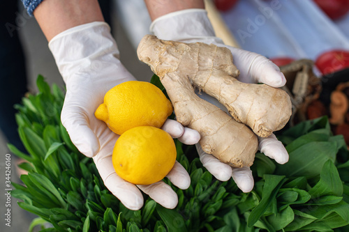 Daily routine in the context of a coronavirus pandemic. The concept of safe shopping. A woman in disposable gloves buys lemon and ginger. Charge of vitamins to fight infection