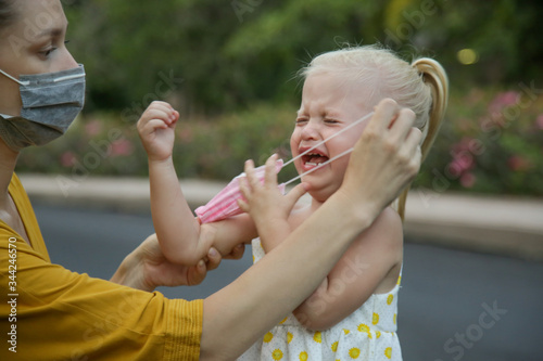 Billede på lærred Mummy struggles to put medical mask on her child's face