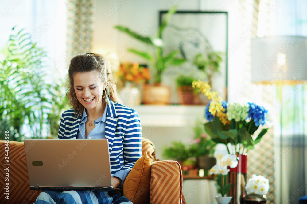 smiling woman with laptop in modern living room in sunny day smiling woman with laptop in modern living room in sunny day