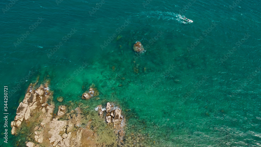 Aerial view background of boat sailing in turquoise sea near a huge reef in summer time taken from drone