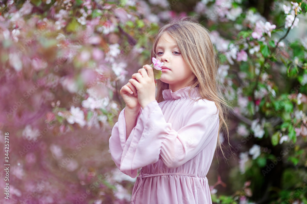 Baby girl with a flower during the apple blossom season in spring Baby girl with a flower during the apple blossom season in spring