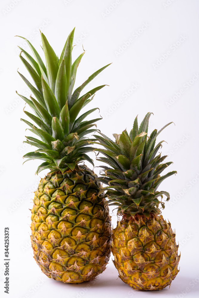 Portrait Of Two Ripe Pineapples Against White Background