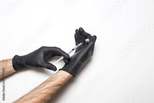 Male hand in a medical glove with a vaccine on a white background. © vfhnb12