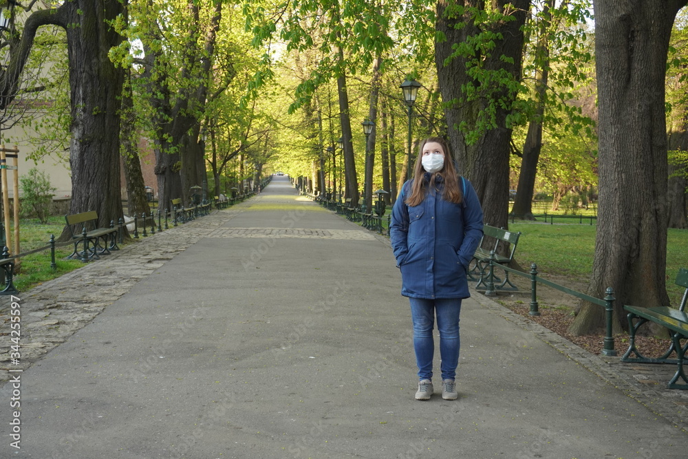 woman in a medical mask walks in empty old city Krakow, Poland. No people or tourists in the city center due to coronavirus infection. woman in a medical mask walks in empty old city Krakow, Poland. No people or tourists in the city center due to coronavirus infection.