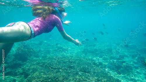 young woman snorkeling in the ocean among fishes
