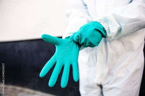 Closeup of man in sterile uniform purring rubber gloves and preparing himself for sterilization from covid-19/ corona virus.
