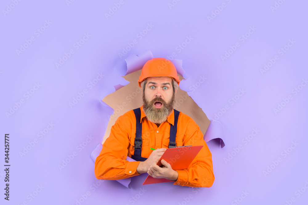 Through paper. Advertising. Repair. Building concept. Engineer making notes. Surprised repairman with folder. Construction worker with folder. Repairman with folder. Man in hard hat. Helmet. Through paper. Advertising. Repair. Building concept. Engineer making notes. Surprised repairman with folder. Construction worker with folder. Repairman with folder. Man in hard hat. Helmet.