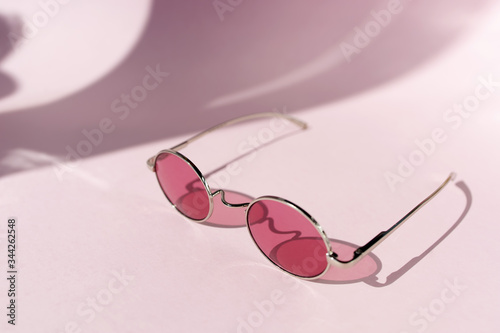 Pink sunglasses on the light pink background. Summer concept. Different shadows. Copy space.Place for text and design.