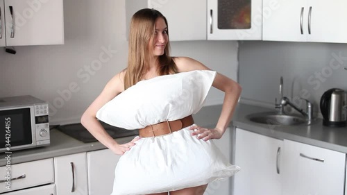 Beautiful girl in a dress of white pillows on a background of the kitchen. Crazy quarantine, challenge 2020 due to house isolation. photo