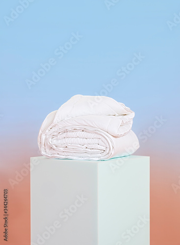 Folded comforter on pastel pedestal