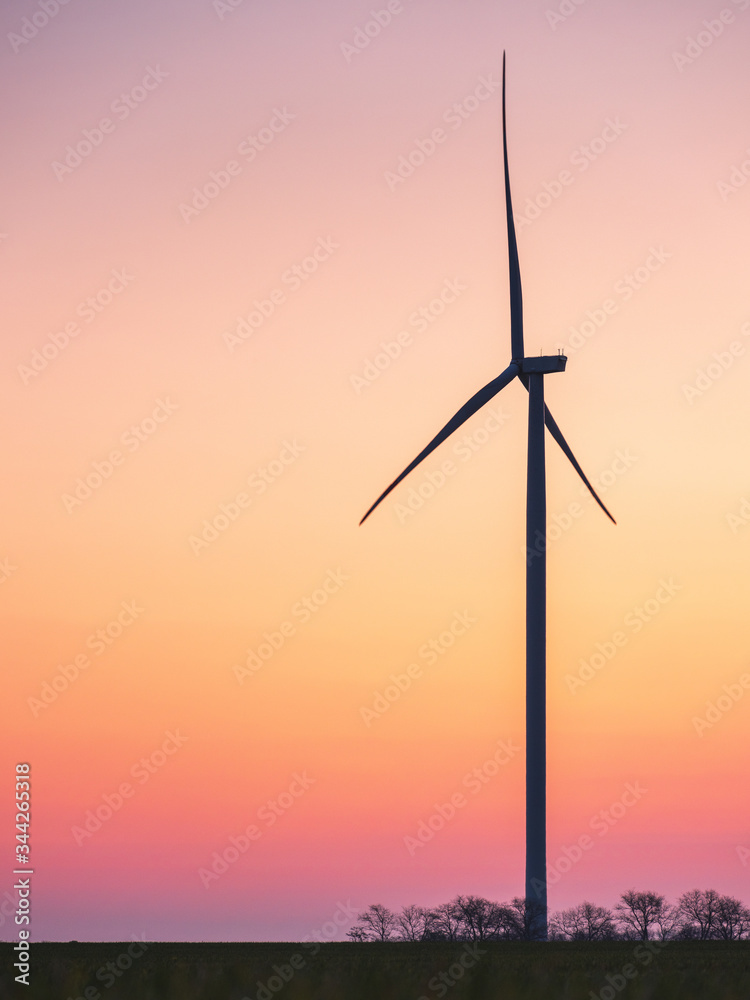 Fototapeta premium silhouette of wind generator in sunset sky with copy space in vertical view