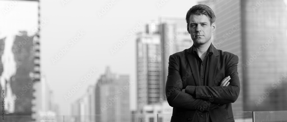 Young handsome businessman in suit with arms crossed against view of the city Young handsome businessman in suit with arms crossed against view of the city