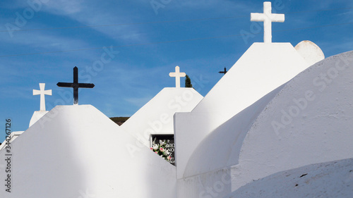 Cruces de varias tumbas blancas con el cielo azul en un día soleado 