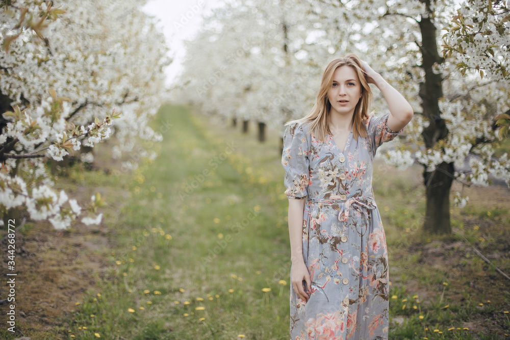 Girl in a flowering garden. Spring garden. Cheerful girl between trees with flowers. Cherry blossom Girl in a flowering garden. Spring garden. Cheerful girl between trees with flowers. Cherry blossom
