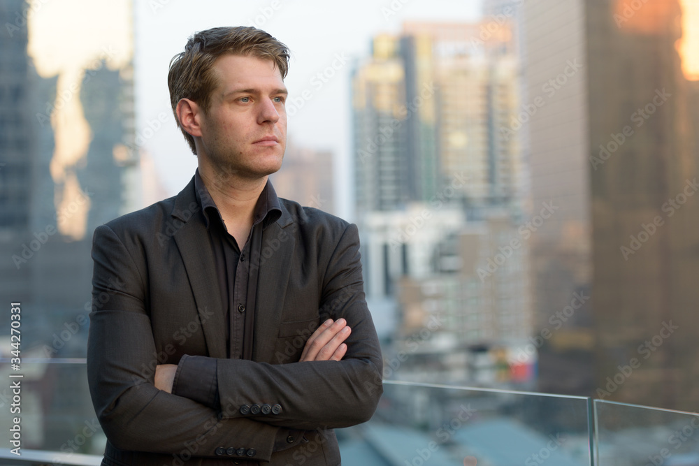 Young handsome businessman in suit thinking and looking at the city Young handsome businessman in suit thinking and looking at the city