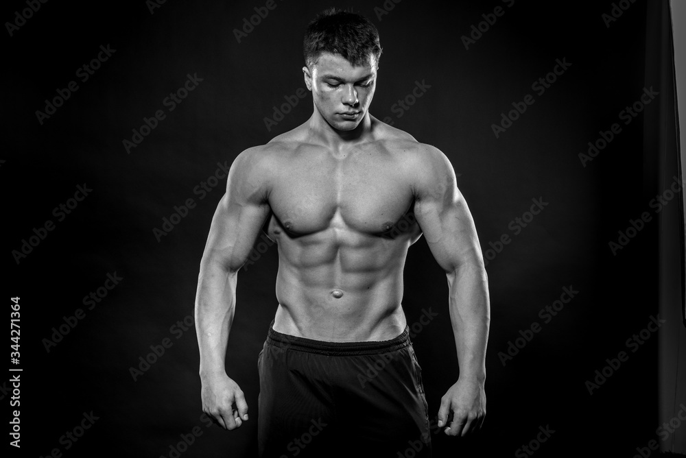 Fototapeta premium Sexy młody sportowiec pozowanie na czarnym tle w Studio. Fitness, kulturystyka, czarno-białe