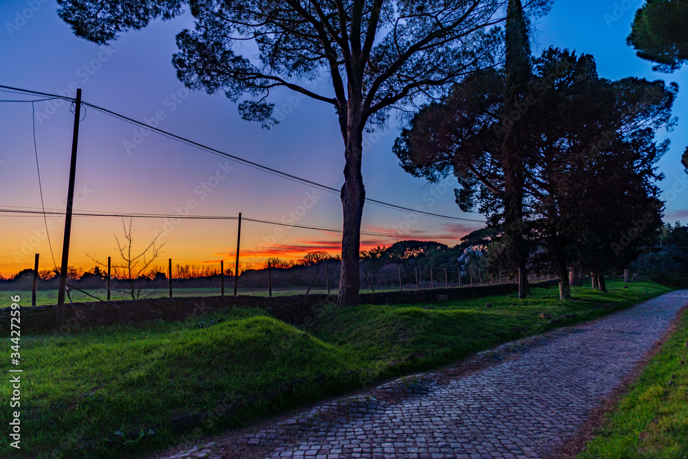 Via Appia Antica, the Appian Way, Rome ancient cobbletone street during sunset or goldenhour Via Appia Antica, the Appian Way, Rome ancient cobbletone street during sunset or goldenhour