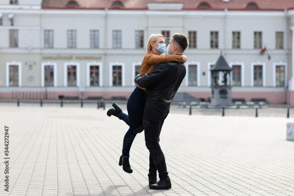 Young couple in masks on city street.