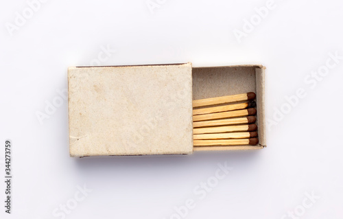 Opened old box of matches isolated on white background, top view. One burnt wooden match among the new ones. Space for design on cardboard box.