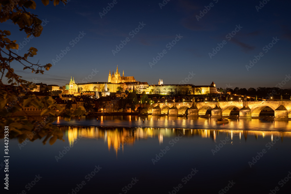 Panoramic view of Prague skyline at night. Charles bridge across the river Vltava and Prague Castle with spires of St. Vitus cathedral. Beautiful calm scene