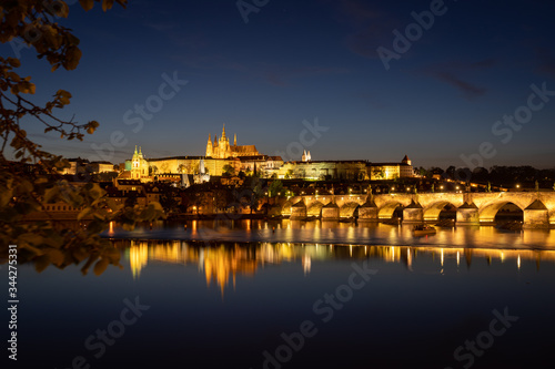 Panoramic view of Prague skyline at night. Charles bridge across the river Vltava and Prague Castle with spires of St. Vitus cathedral. Beautiful calm scene