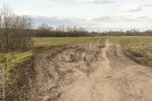 dirt damaged rural spring road in a field. concept of problem with the roads