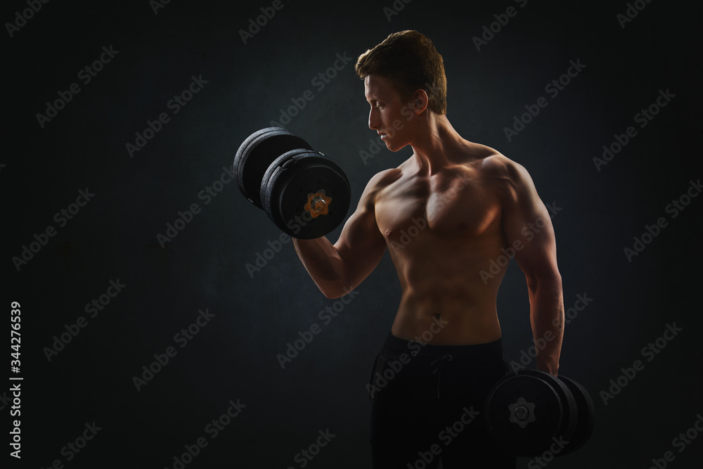 Muscular man with dumbbells on black background
