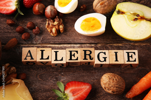 Allergy food concept. Allergy food as almonds, milk, cheese, strawberry, eggs, peanuts and .crustaceans or shrimps with wooden letter in german allergie