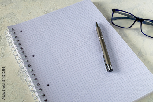 Large notebook, pen and glasses on a light background