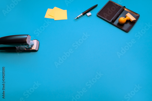 Ein schöner Schreibtisch Desktop als Hintergrund in Blau mit einem Stempel und Notizblöcken und einem Füller und einem Tacker.  photo