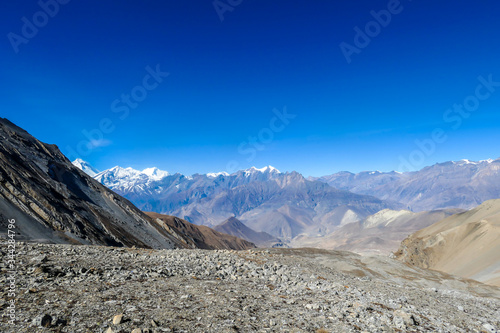 A panoramic view on dry Himalayan valley, located in Mustang region, Annapurna Circuit Trek in Nepal. In the back there is snow capped Dhaulagiri I. Barren and steep slopes. Harsh condition. © Chris