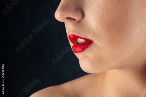 Close up beauty portrait of young adorable red-haired woman with bare shoulders in studio on dark background