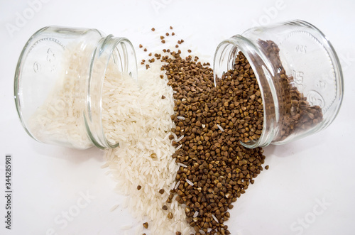 rice and buckwheat in glass jars on white. View from above.