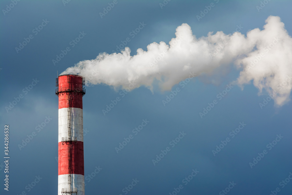 A smoking chimney in a blue sky. The emission of harmful gases into the atmosphere, greenhouse efekt. Air pollution, Closeup of one big smoking pipe. A smoking chimney in a blue sky. The emission of harmful gases into the atmosphere, greenhouse efekt. Air pollution, Closeup of one big smoking pipe.