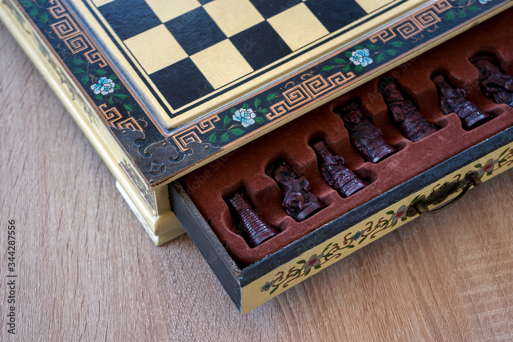Close-up of a chess table. Beautiful box with floral decorations. Opened drawer with chess pieces Close-up of a chess table. Beautiful box with floral decorations. Opened drawer with chess pieces