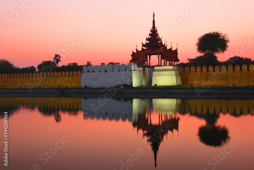 Night view to the silhouettes of the Fort or Royal Palace in Mandalay, Myanmar (Burma) with red sunset sky